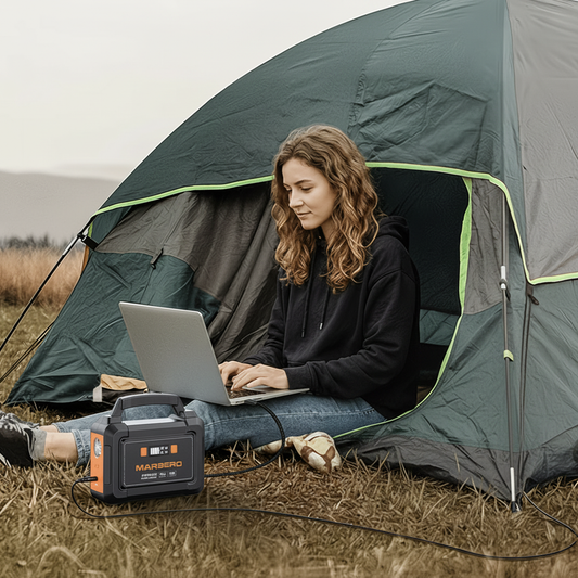 Woman using laptop at campsite with Marbero portable power station and solar panel